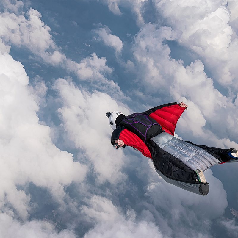 Man gliding above the clouds in a wingsuit.