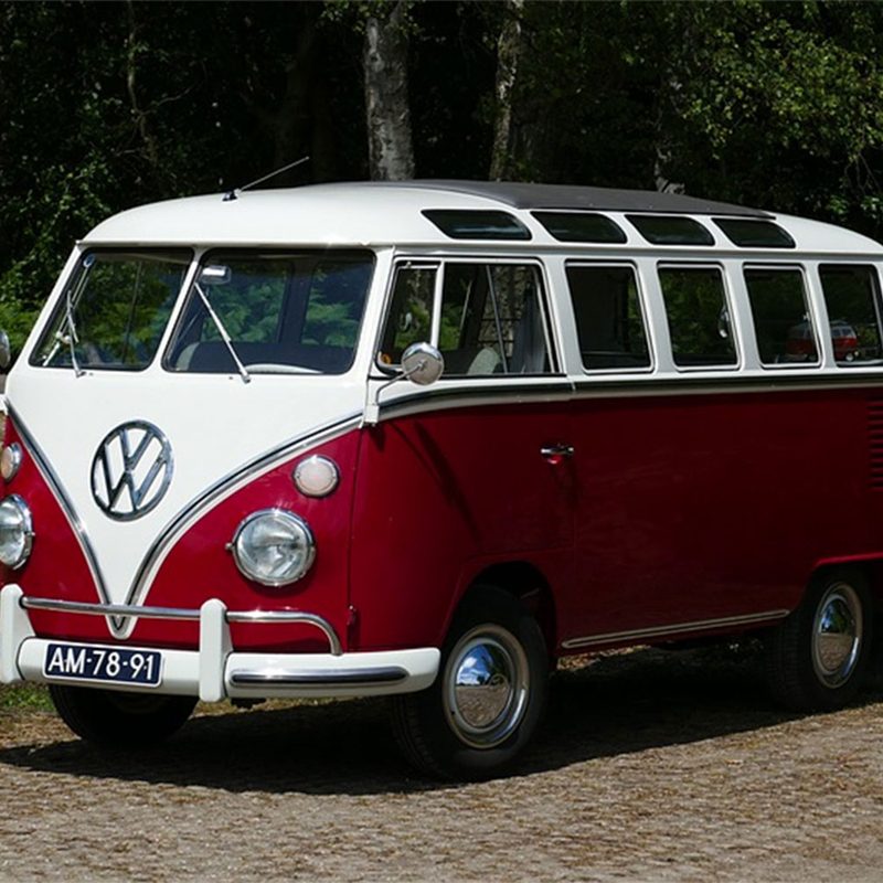 Classic red and white Volkswagen Camper Van parked on a dirt road.