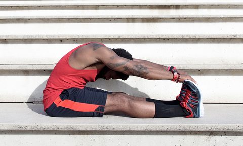 Man stretching his legs and arms before working out.