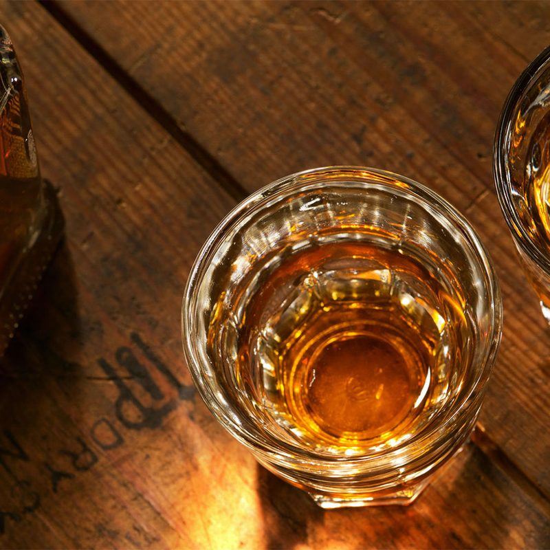 A bottle of whiskey with two glasses of whiskey