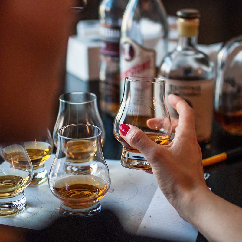 A woman's hand holding a glass of bourbon