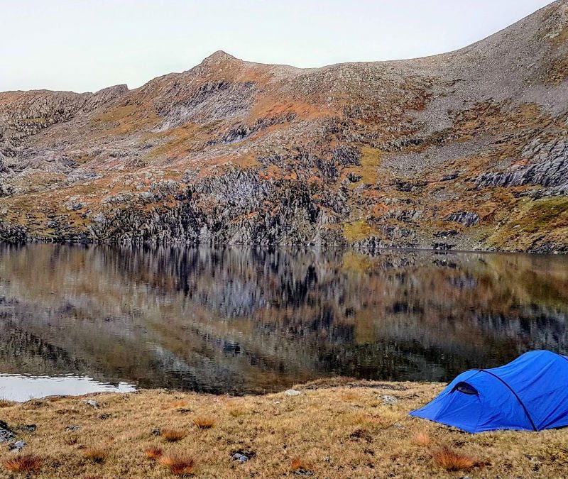 A blue tent near a body of water.