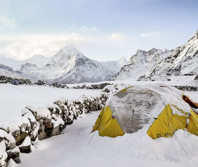 A yellow tent on a snowy mountain.