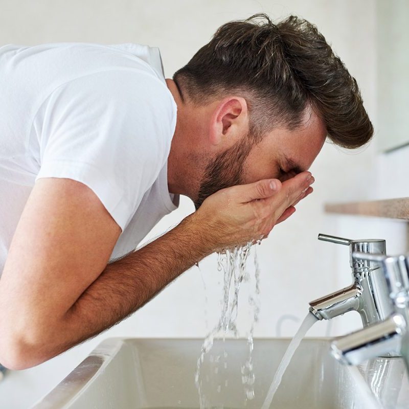 Man washing his face in the bathroom.