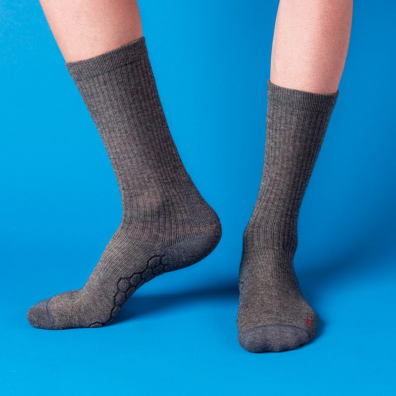 Feet wearing merino wool socks on a blue background.