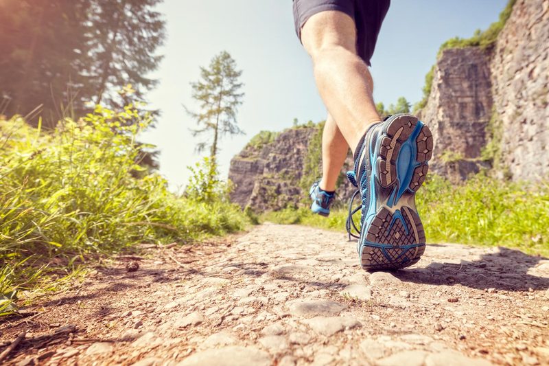 A close up of a trail runner's feet as they run away from the camera on a rocky trail