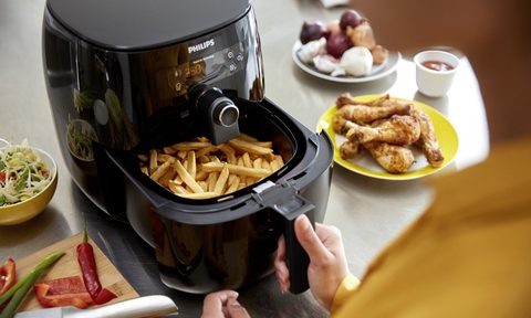 Someone in the kitchen using an air fryer to cook.