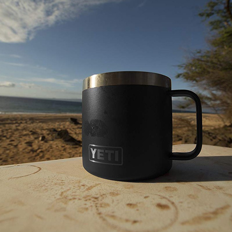 A black Yeti mug on a table outside.