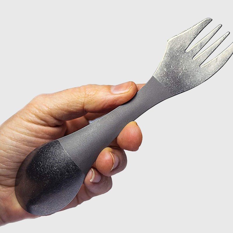 A hand holding a metal spork.