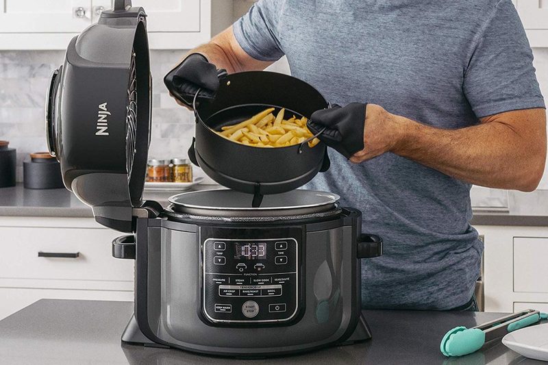 A person using an air fryer to cook dinner.