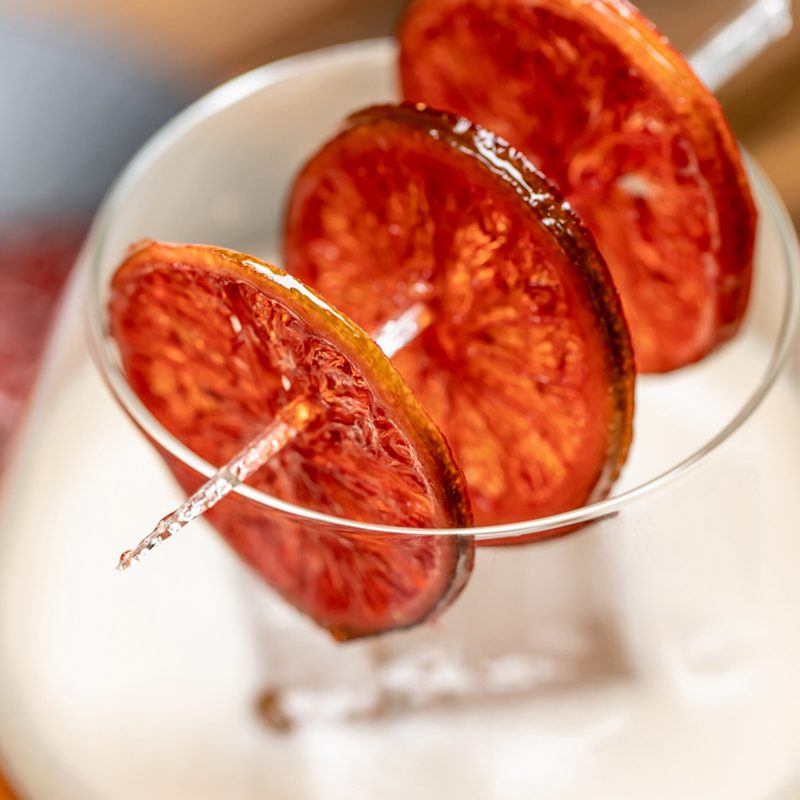 A close-up of skewered, candied limewheels on a glass of Sole Rosso