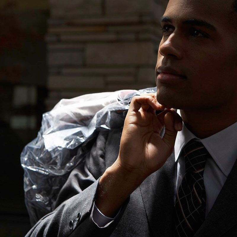 Man carrying a suit in a cleaning bag.