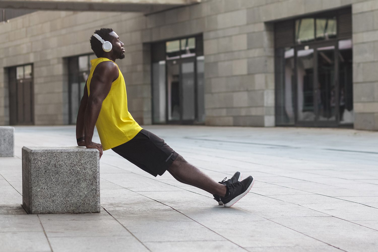 Man leaning against a concrete block doing dips.