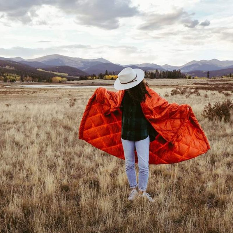 person standing in a field with blanket over their shoulders.