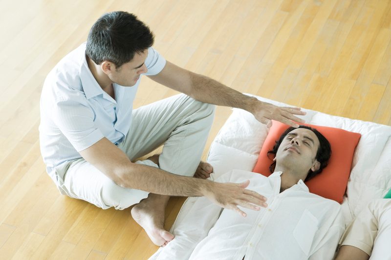 A man performing reiki on a person lying down
