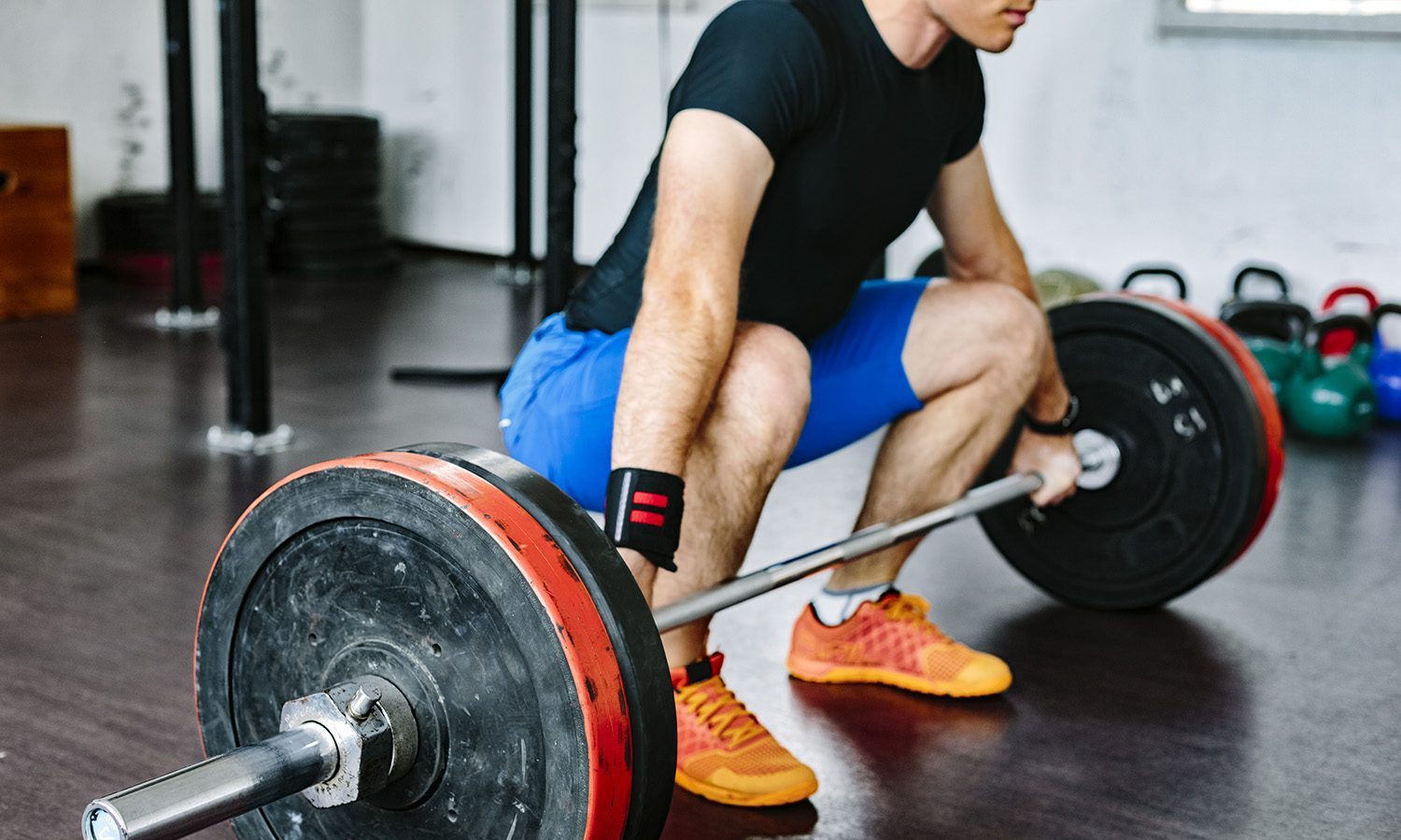 A man wearing a black shirt as he does a deadlift in the gym