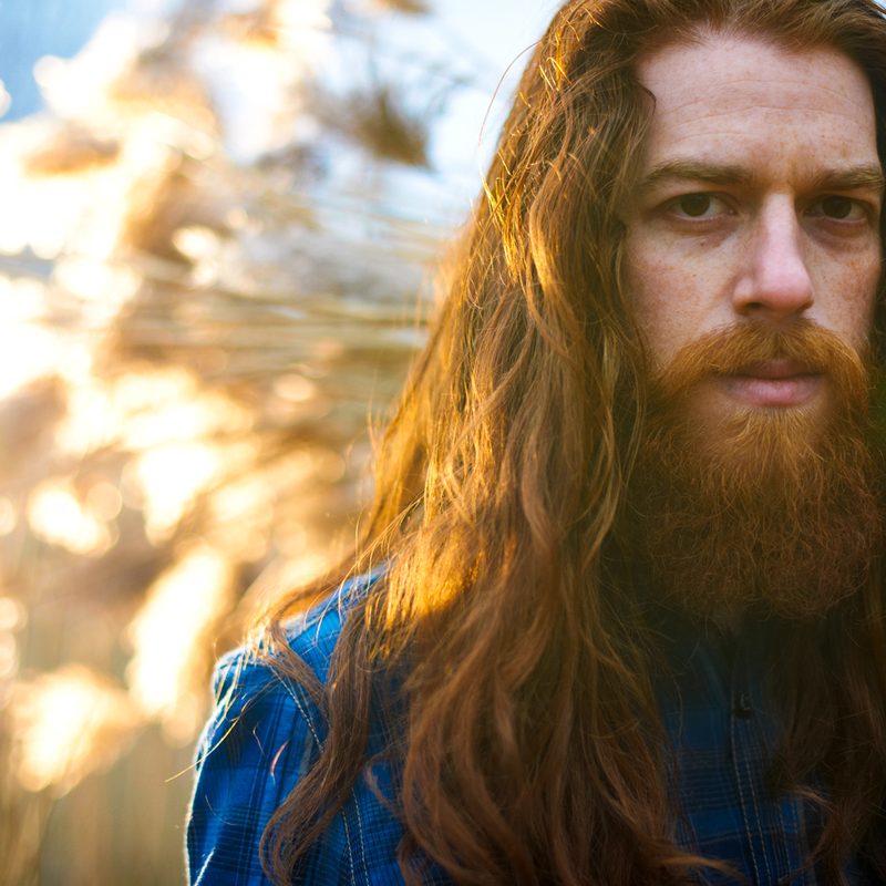 Man with long red hair in a field