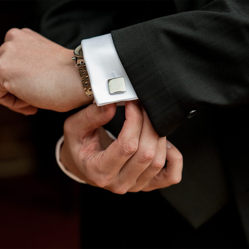 Man's arms and hands adjusting his tuxedo cuff links