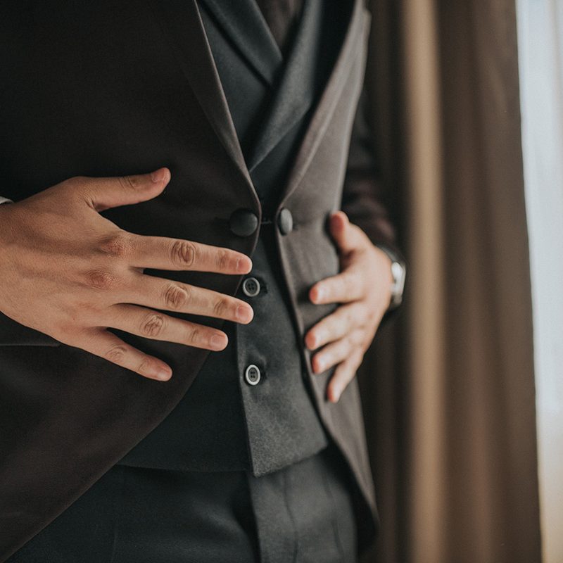 Pair of man's hands holding his jacket and waist coat
