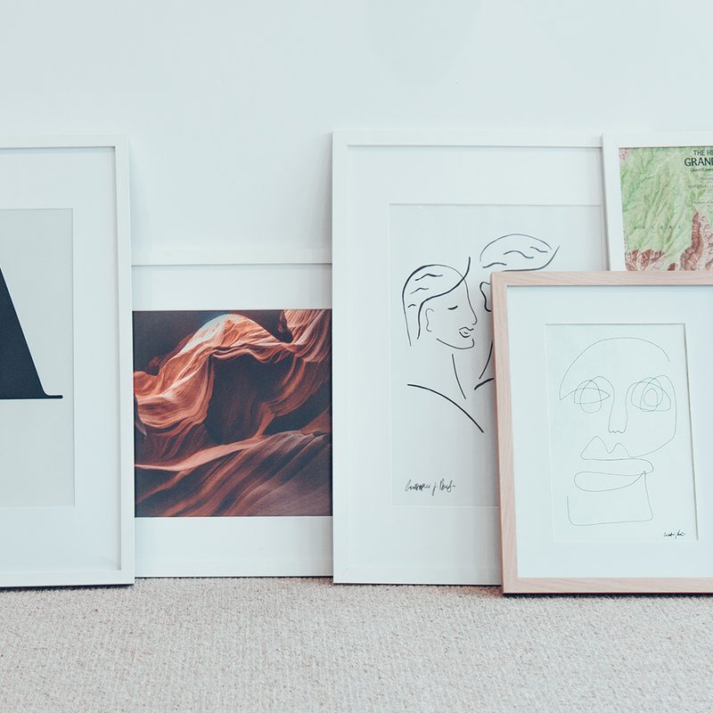 Framed prints leaning up against a wall.