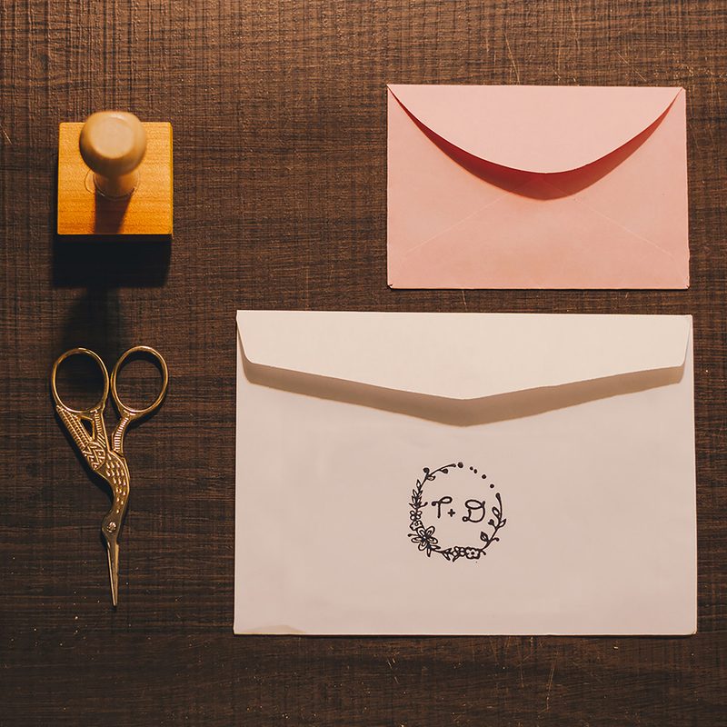 A monogrammed set showing two envelopes, a stamp, and scissors.