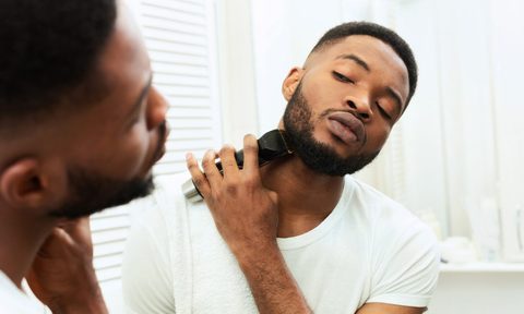 A man trimming his beard in the mirror