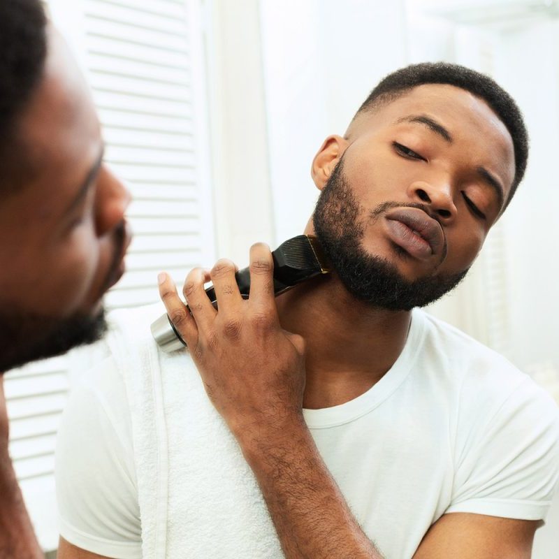 A man trimming his beard in the mirror