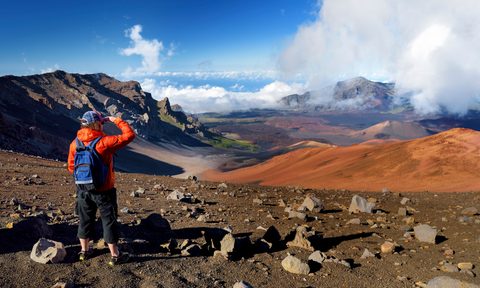 Tourist hiking in Haleakala volcano crater on the Sliding Sands trail. Beautiful view of the crater floor and the cinder cones below. Maui, Hawaii, USA.