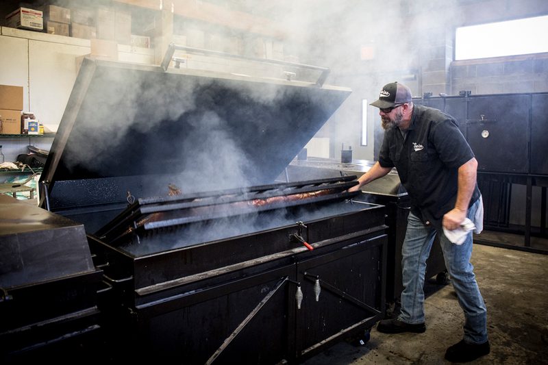 A man smoking turkeys in a smoker.