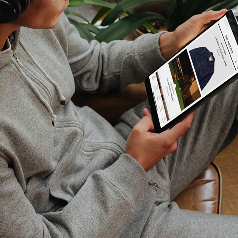 A man using a tablet to shop for clothes on Mr Porter's website.