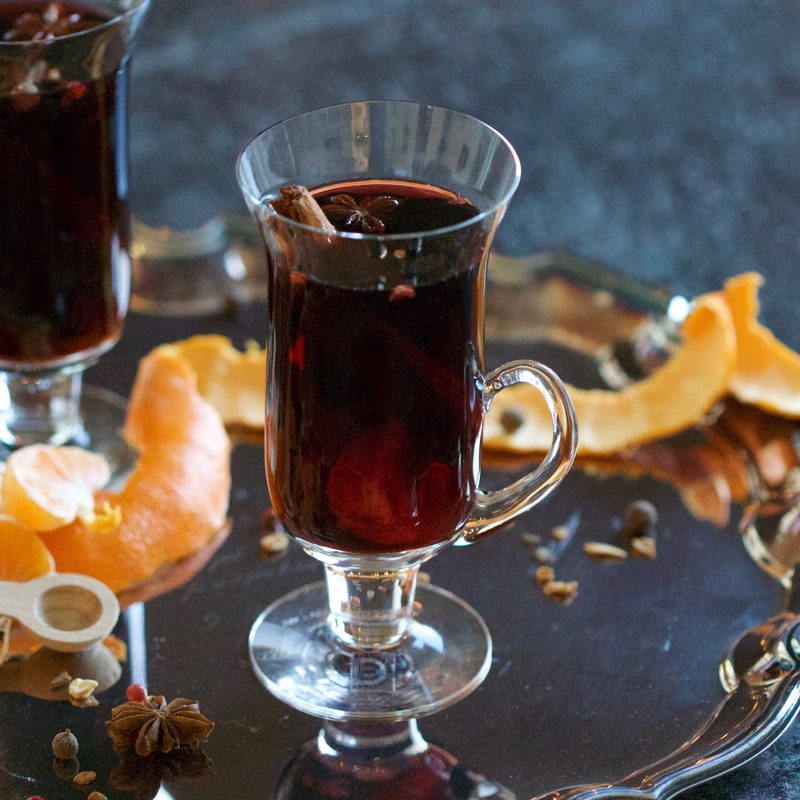 mulled wine in a glass sitting on a tray.