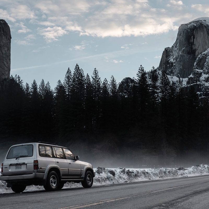 An SUV driving on a mountain pass in winter.
