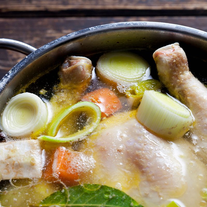 Chicken soup stock with vegetables on a pot.