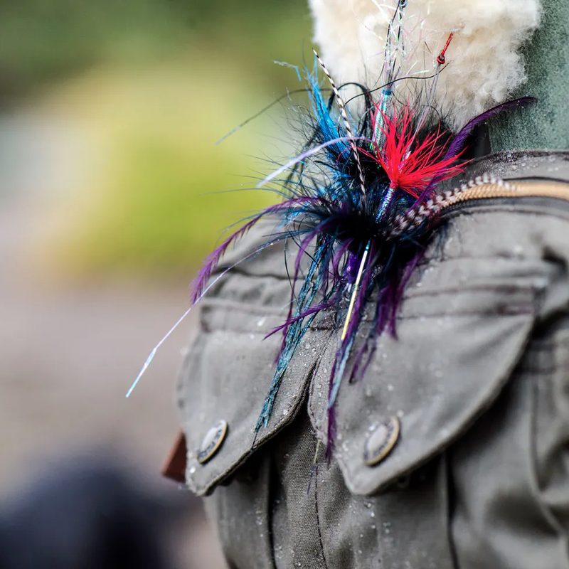 Closeup of colorful flies pinned to a fly fishing bag.