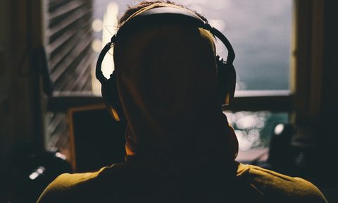 Wearing headphones listing to a podcast on a laptop
