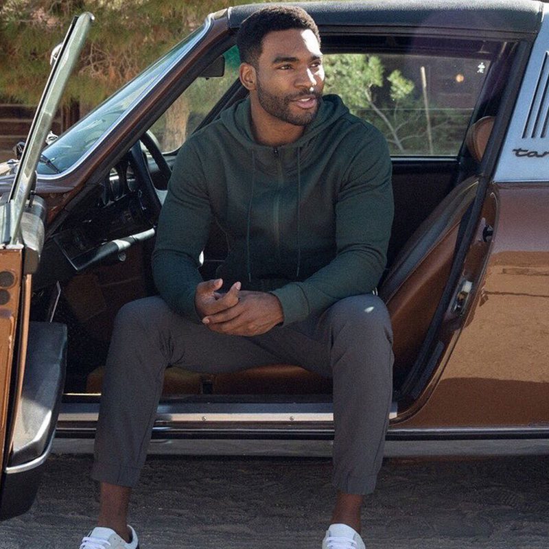 A man sitting on his car's driver seat. wearing Olivers workout gear