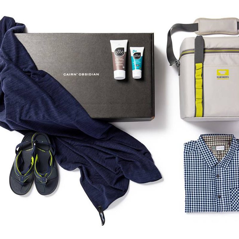 The Cairn box with outdoor apparel on a white backdrop.