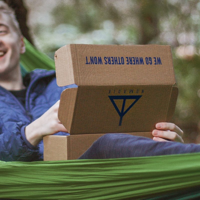 Man in hammock opening a Nomadik subscription box.