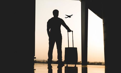 Traveler watching planes from an airport window.