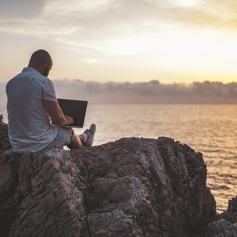Man working on a laptop on the beach.