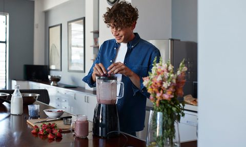 man making smoothie in kitchen