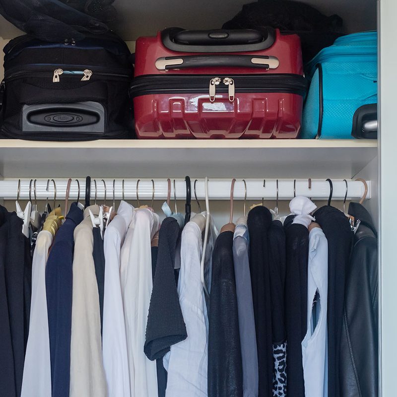 Closet with luggage and hanging clothes
