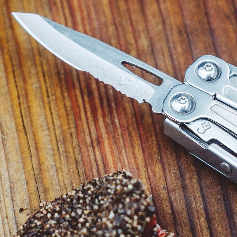 leatherman multi tool sitting next to a piece of cut sausage.