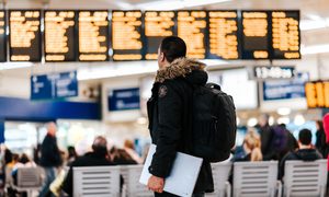 A person in the airport looking at the flight board.