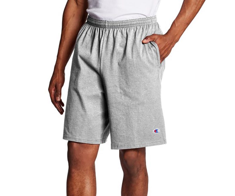 A man with his hand in his pocket is seen wearing a gray Champion Shorts.