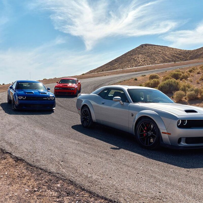 Dodge Challenger SRT Hellcats lined up on a race track in the desert.