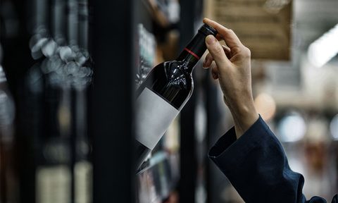 Person grabbing a wine bottle