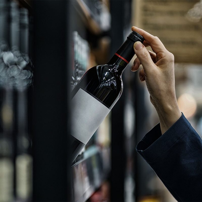 Person grabbing a wine bottle