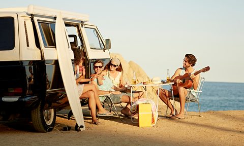 Friends relaxing outside mini van at beach