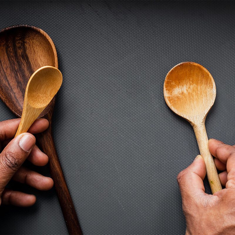 Wooden spoons being held over a counter